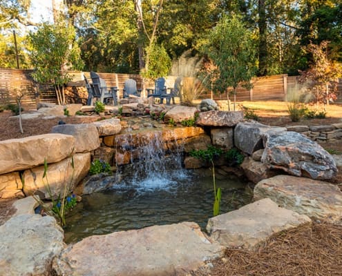 A peaceful backyard retreat that includes a water feature and fire pit sitting area. This outdoor living space was designed and built by R&R Landscaping.