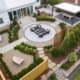 A classic landscape design with modern twists, including a fire pit, beautiful plants and shrubs, a covered dining table, and custom rock benches engraved with the family's favorite quotes. This outdoor living space was designed and built by R&R Landscaping.